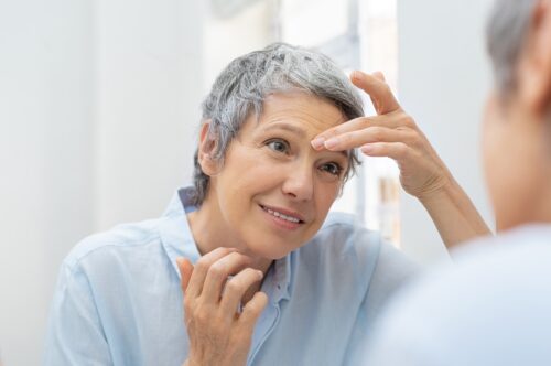 woman examining her face in the mirror